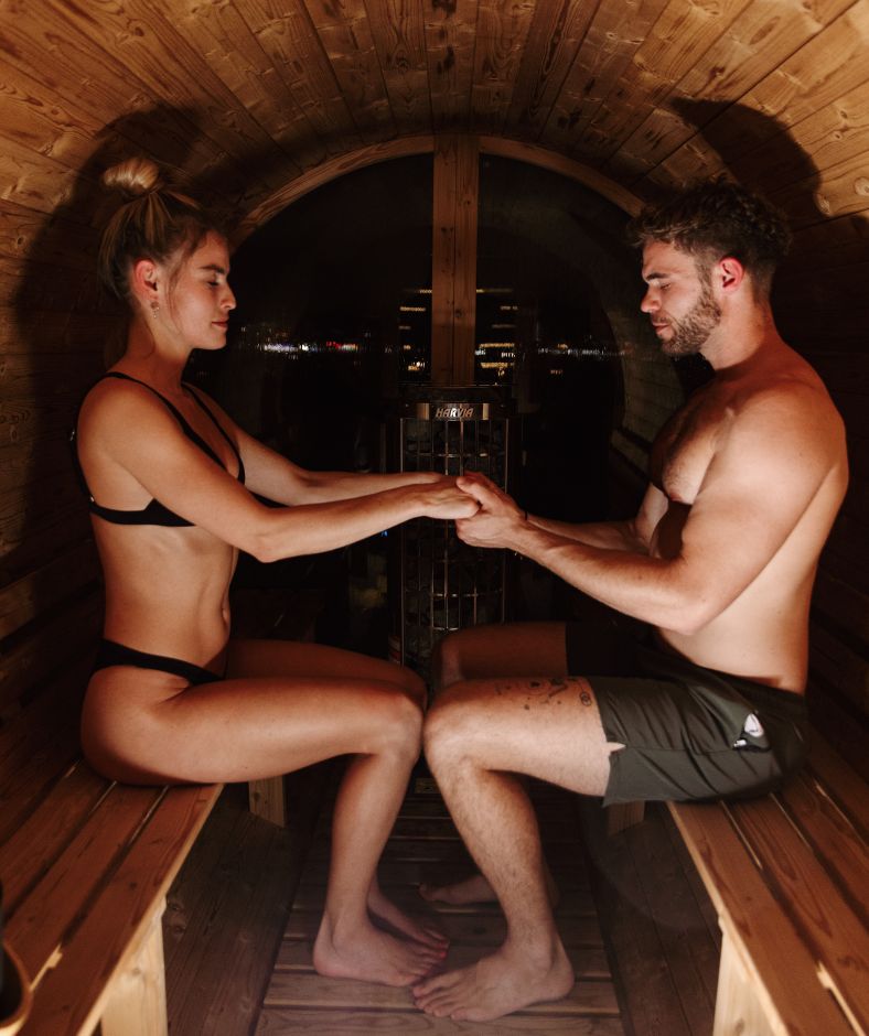 A couple holds hands during meditation in Redwood Outdoors panorama sauna.