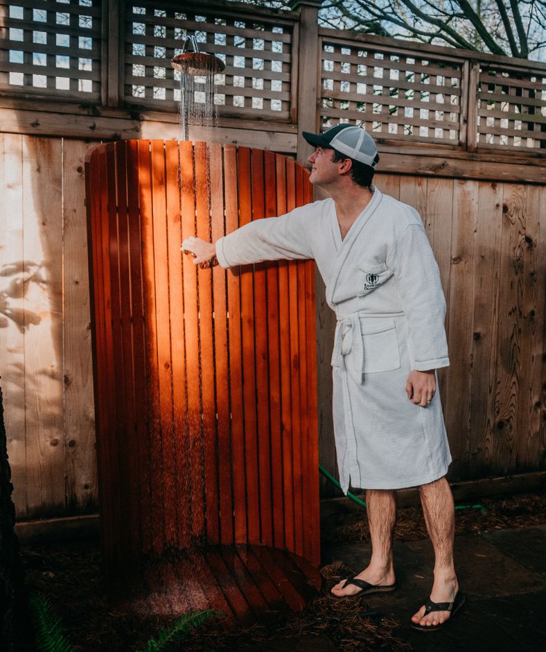 Founder of Redwood Outdoors, Killian Lannen, uses his Redwood Outdoors shower to rinse off before getting into the sauna.